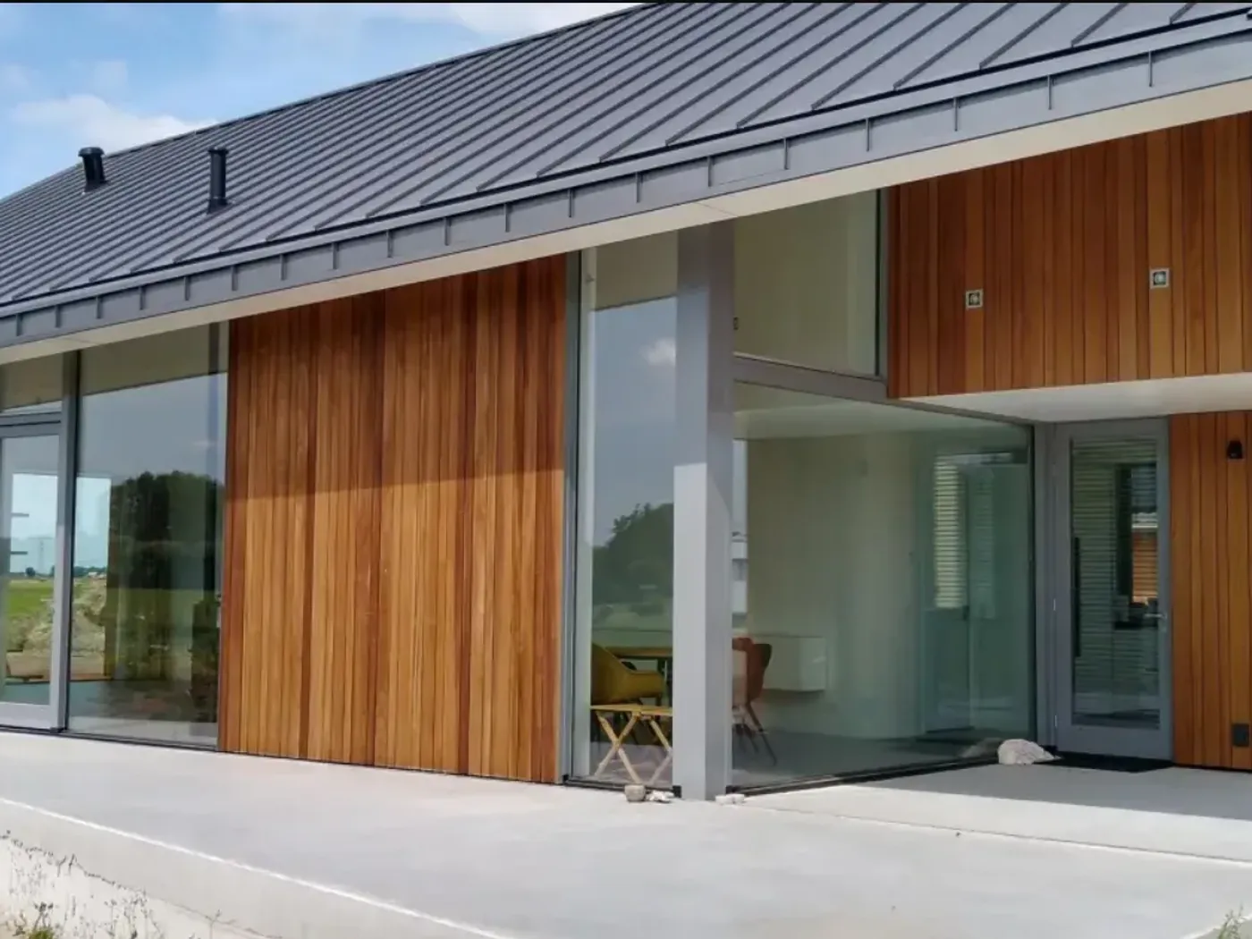 Woonhuis met houten gevelbekleding en een klikfels-dak in donkere staande fels