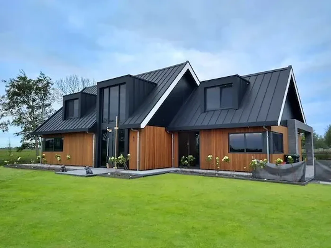 Woonhuis met een zwart klikfels-dak, dakkapellen en houten geveldelen