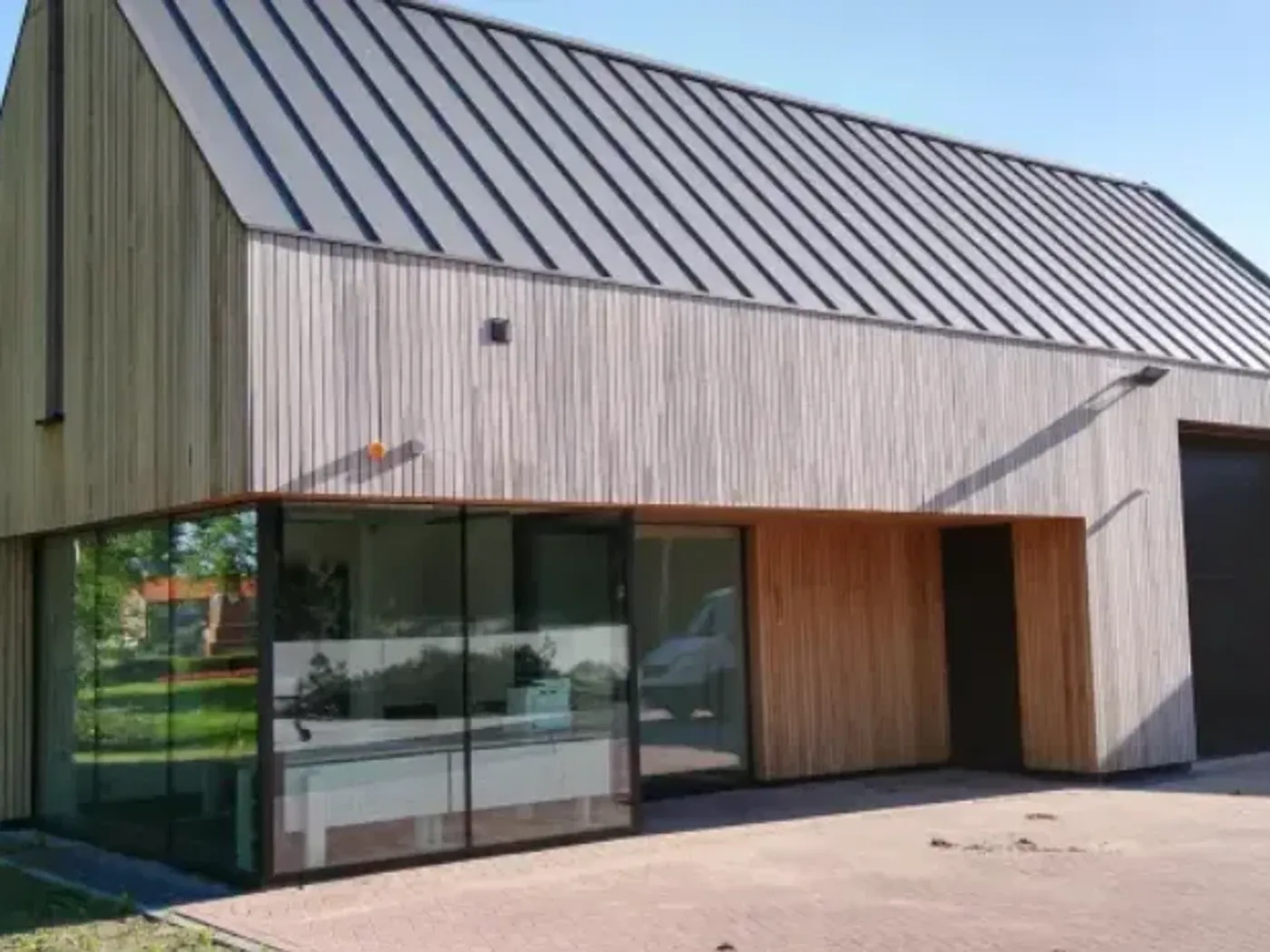 Bedrijfsgebouw met lichte houten gevel en een klikfels-dak in staande fels