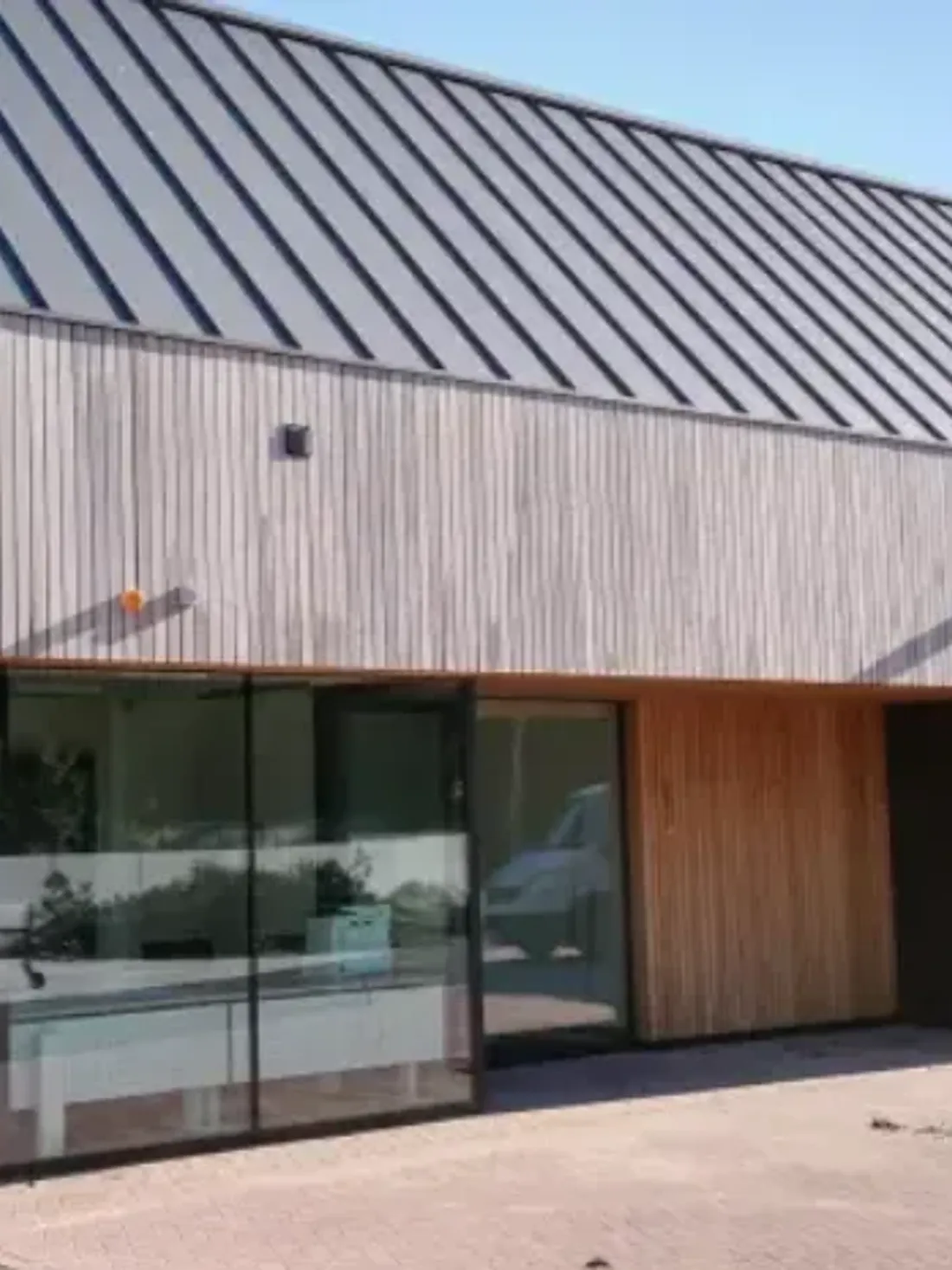 Bedrijfsgebouw met licht houten gevel en een KlikZink-dak in staande fels